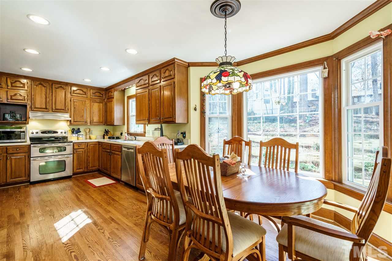 2212 Tyson Street Raleigh, NC 27612 - Photo 9 of 24 a kitchen with stainless steel appliances granite countertop a stove a refrigerator a kitchen island a dining table and chairs with wooden floor