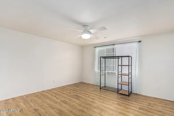 an empty room with wooden floor and ceiling fan
