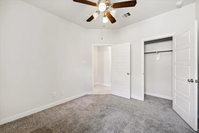 an empty room with closet and a chandelier fan