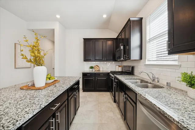 a kitchen with granite countertop stainless steel appliances a sink stove and cabinets