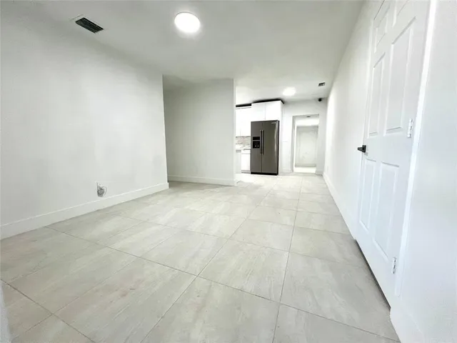 an empty room with kitchen view and a hallway