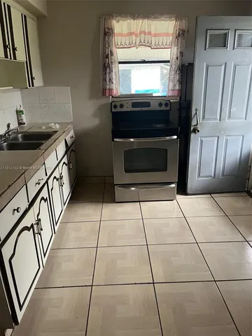 a kitchen with granite countertop a stove a sink and a refrigerator
