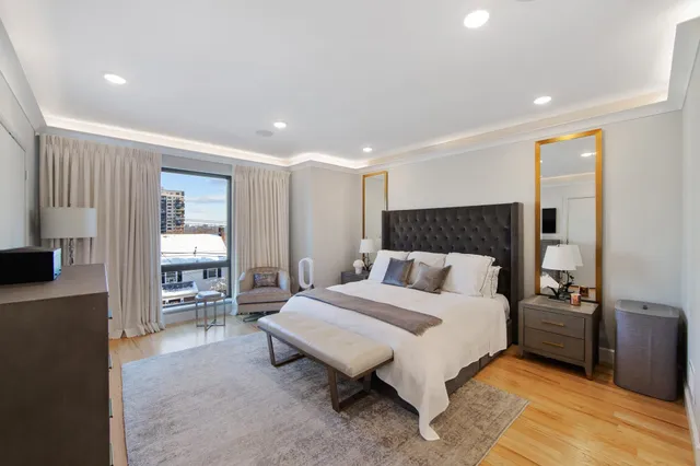 a spacious bedroom with a bed a couch and large window