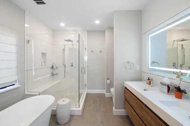 a bathroom with a bathtub shower sink mirror and toilet