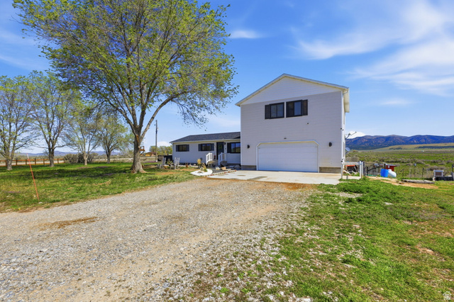 830 North Stone Road Snowville, UT 84336 - Photo 68 of 69 View of front of property featuring a garage, driveway, a patio, a front lawn, and a mountain view