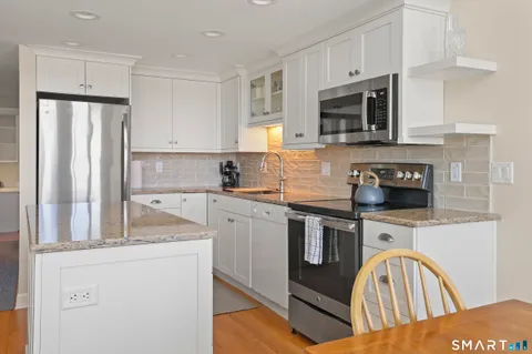 a kitchen with stainless steel appliances granite countertop a stove a sink and a microwave