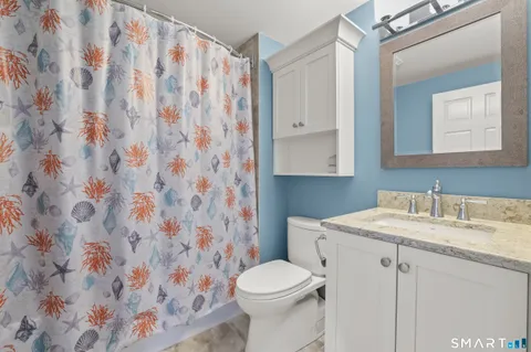 a bathroom with a granite countertop sink a toilet and a mirror