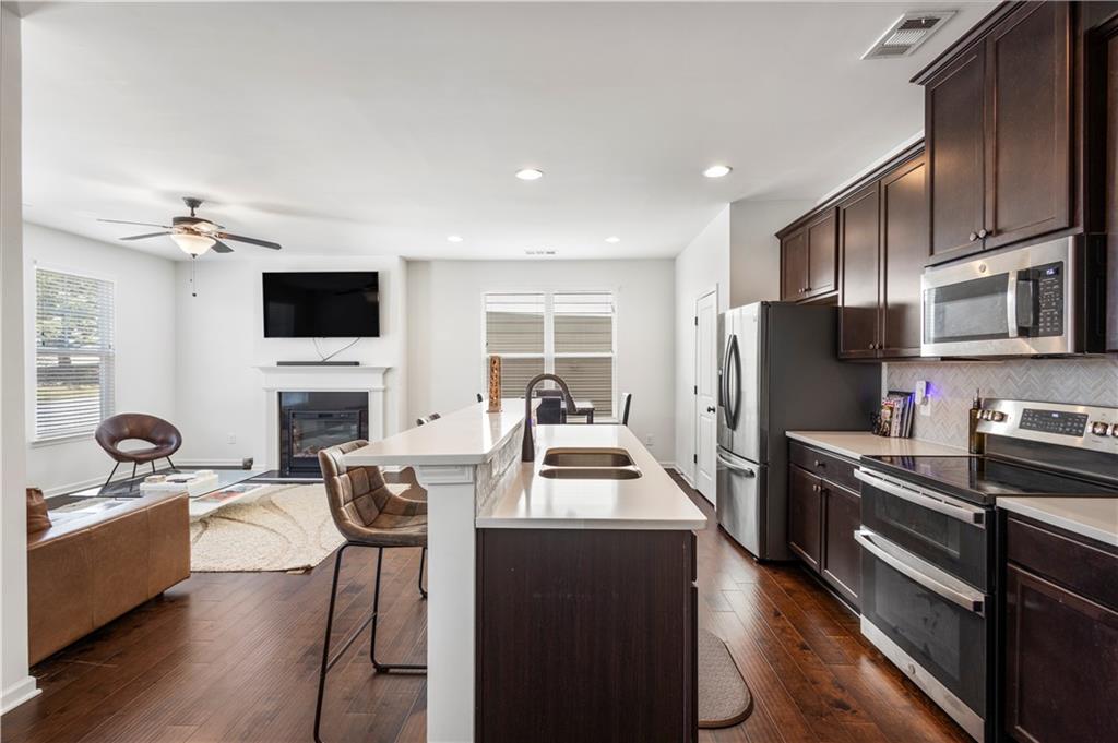 869 Venture Way Atlanta, GA 30331 - Photo 9 of 27 a kitchen with kitchen island granite countertop a stove top oven a sink dishwasher a dining table and chairs with wooden floor