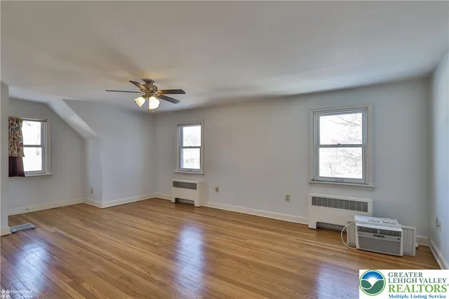 a view of empty room with wooden floor and fan
