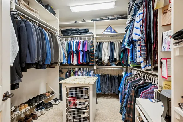 a view of walk in closet with clothes and shoes