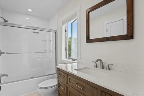 a bathroom with a granite countertop sink toilet a mirror and shower