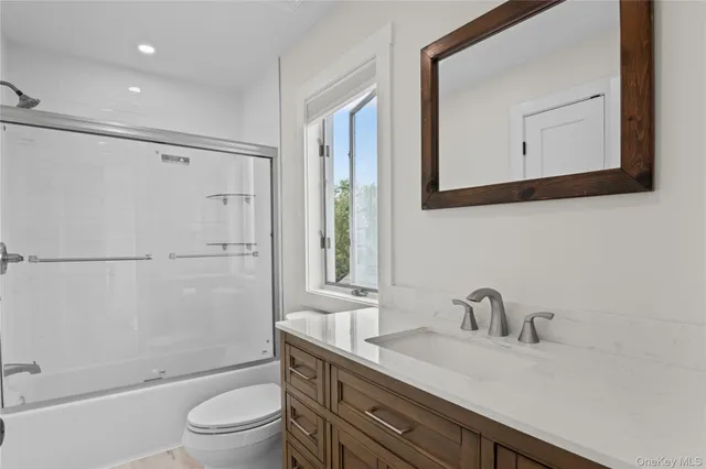 a bathroom with a granite countertop sink toilet a mirror and shower