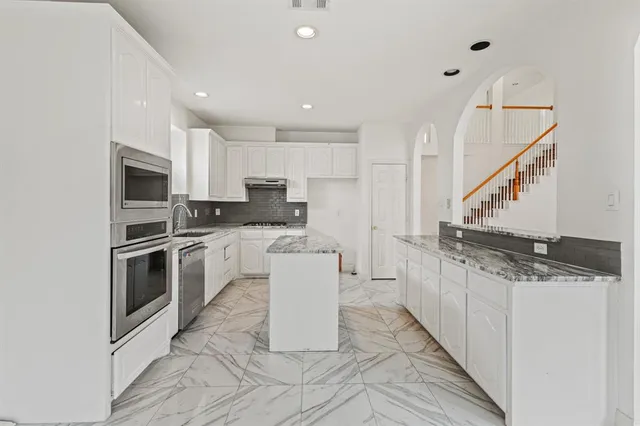 a kitchen with granite countertop a stove top oven and cabinets