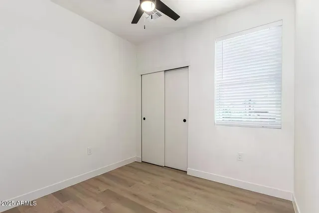 an empty room with ceiling fan and window