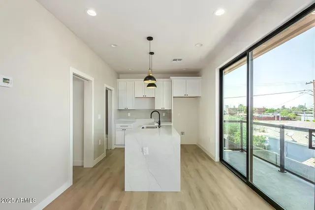 a kitchen with stainless steel appliances granite countertop a refrigerator a sink dishwasher a stove and white countertops with wooden floor