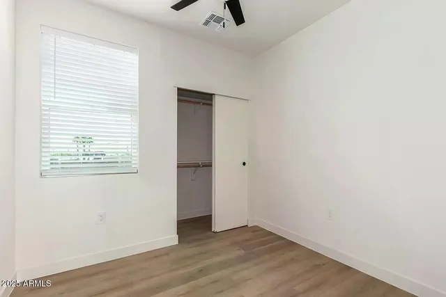 an empty room with wooden floor and windows