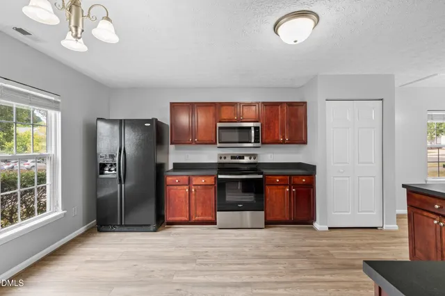 a view of kitchen with stainless steel appliances granite countertop a refrigerator and a stove top oven