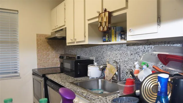 a kitchen with stainless steel appliances granite countertop a sink a stove and cabinets