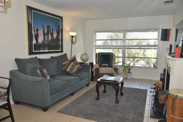 a living room with furniture a large window and a flat screen tv with exposed radiator