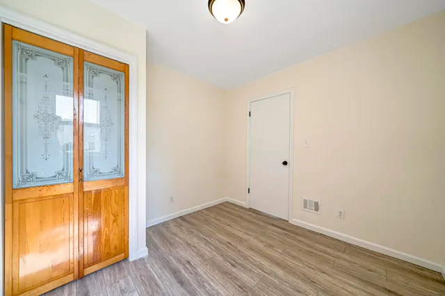 a view of an empty room with wooden floor and windows