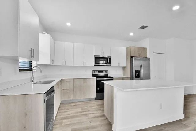 a kitchen with kitchen island a sink stainless steel appliances and white cabinets