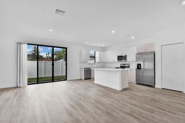 a large white kitchen with a refrigerator a stove top oven and white cabinets