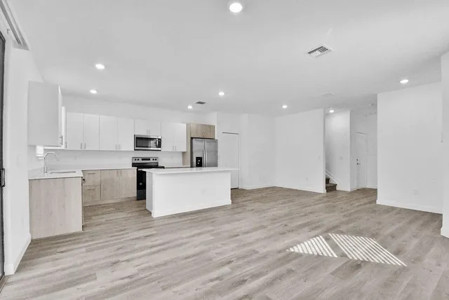 a view of kitchen with kitchen island a sink wooden floor and stainless steel appliances