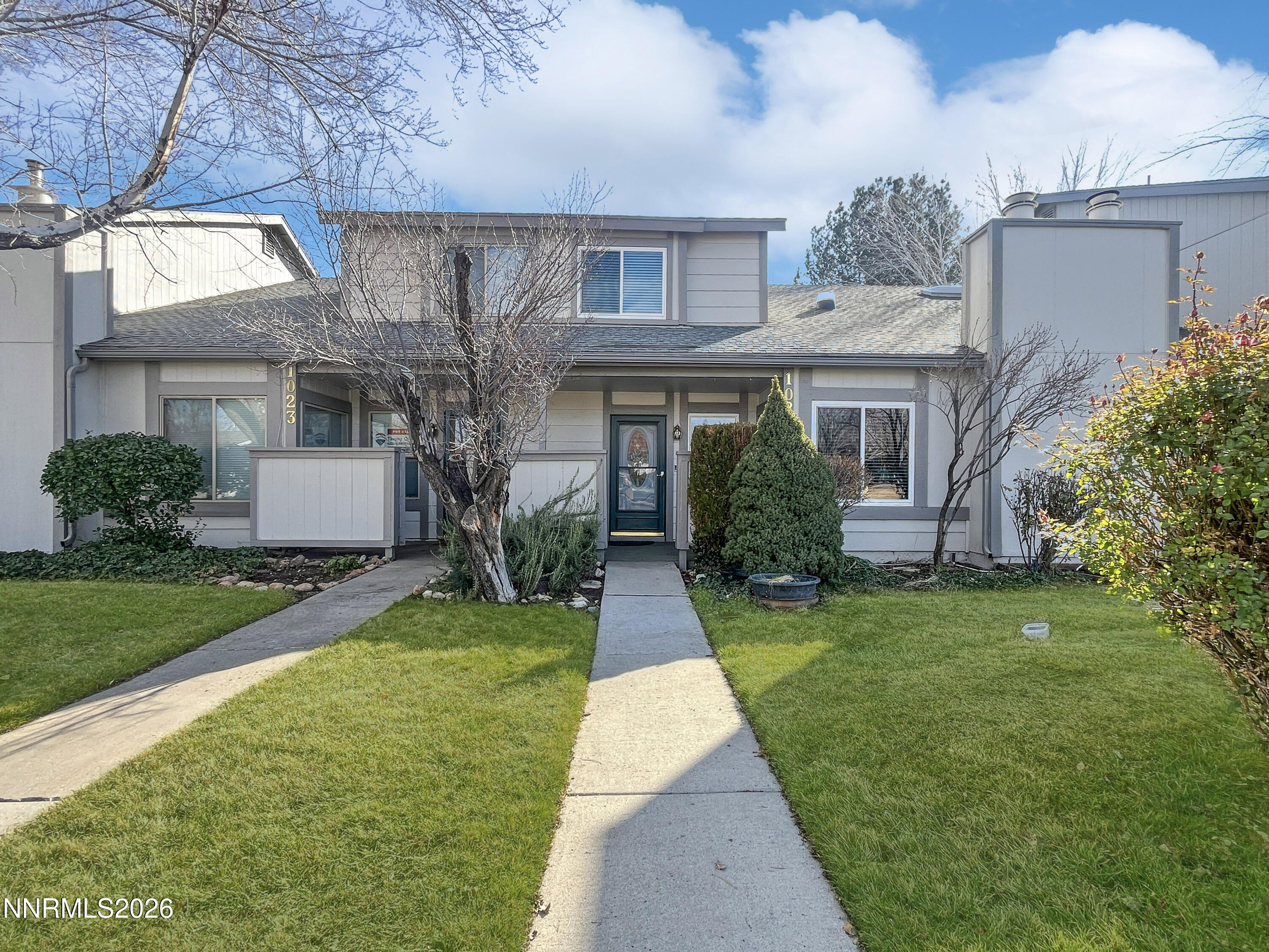 a front view of a house with a yard and trees