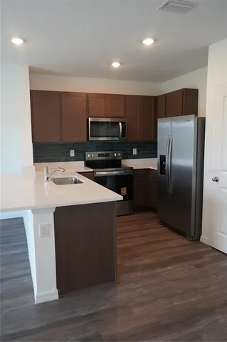 a kitchen with kitchen island stainless steel appliances a sink cabinets and a counter top space