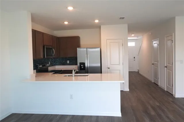 a large kitchen with stainless steel appliances a large counter top a stove a sink and a refrigerator