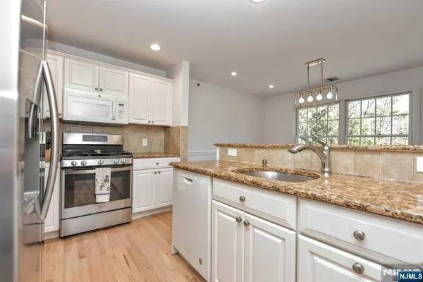 a kitchen with granite countertop a sink stainless steel appliances and cabinets