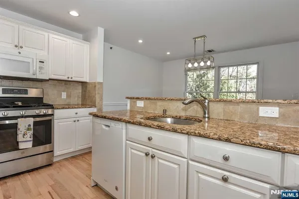 a kitchen with granite countertop white cabinets and white stainless steel appliances