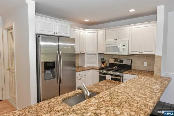 a kitchen with stainless steel appliances kitchen island granite countertop a refrigerator and a stove top oven