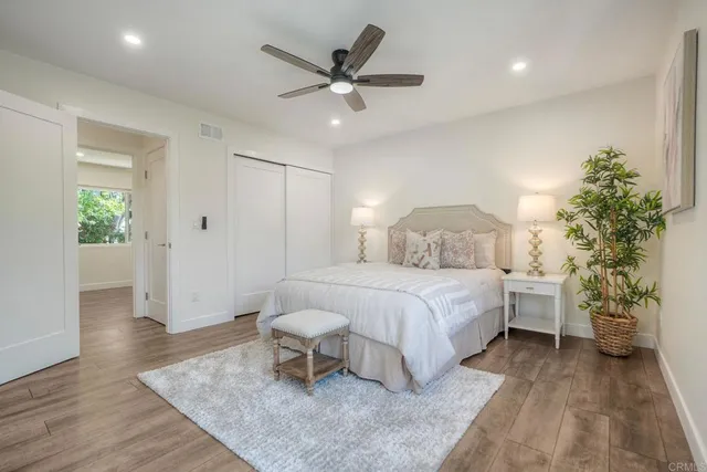 a bedroom with a bed potted plant with the wooden floor