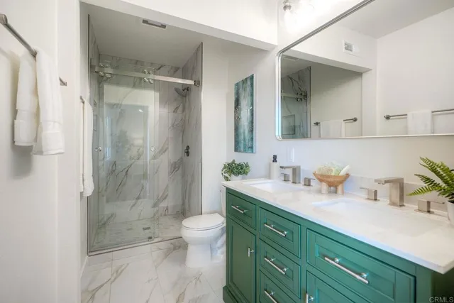 a bathroom with a granite countertop sink a toilet and shower