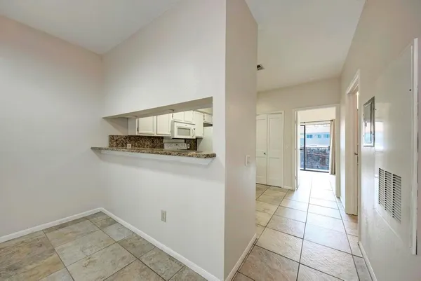 a view of a refrigerator in kitchen and an empty room