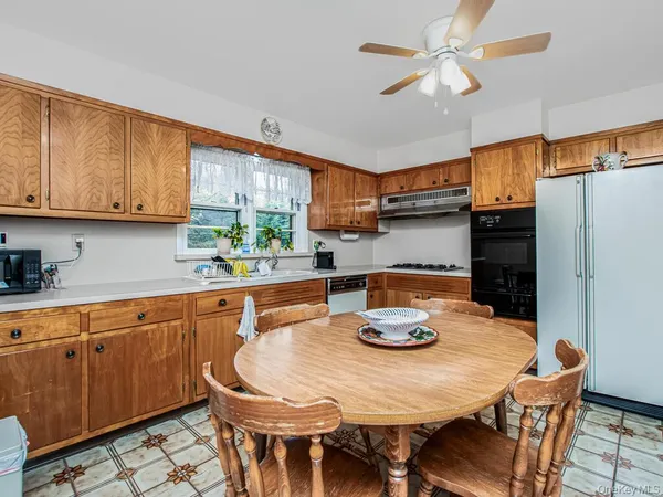 a kitchen with stainless steel appliances granite countertop a dining table chairs and a refrigerator