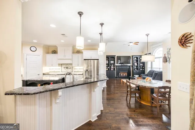 a kitchen with stainless steel appliances kitchen island granite countertop a table chairs and a refrigerator