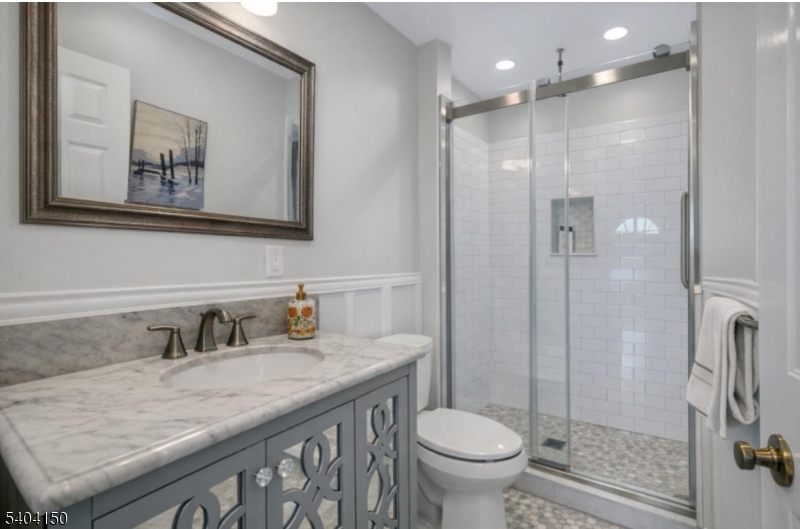 31 Garfield Avenue Madison, NJ 07940 - Photo 22 of 47 a bathroom with a granite countertop sink a toilet a mirror and shower