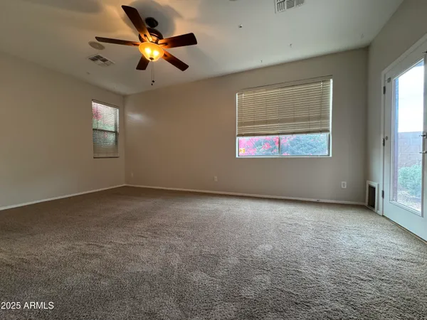an empty room with windows and ceiling fan