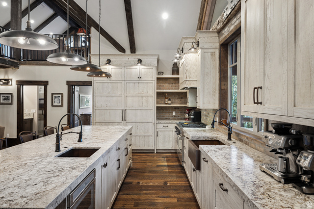 1667 West Tollgate Cyn Road Coalville, UT 84017 - Photo 24 of 61 Spacious kitchen featuring a large island with an undermount sink, granite countertops, wood-finish flooring, custom cabinetry, and exposed wood beams