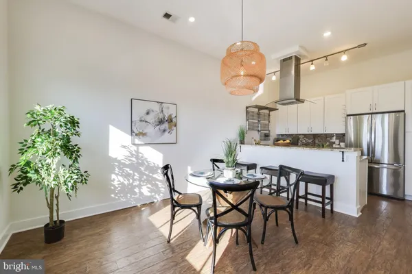 a kitchen with granite countertop a table a stove a sink a refrigerator and a dining table with wooden floor
