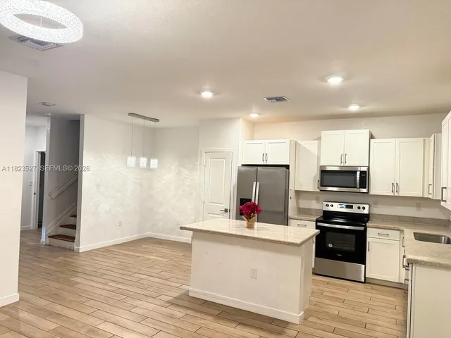 a kitchen with granite countertop a refrigerator and a stove top oven