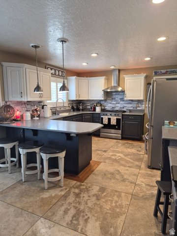 1697 West 2450 Vernal, UT 84078 - Photo 11 of 36 Kitchen featuring a kitchen bar, a peninsula, stainless steel appliances, backsplash, and a textured ceiling