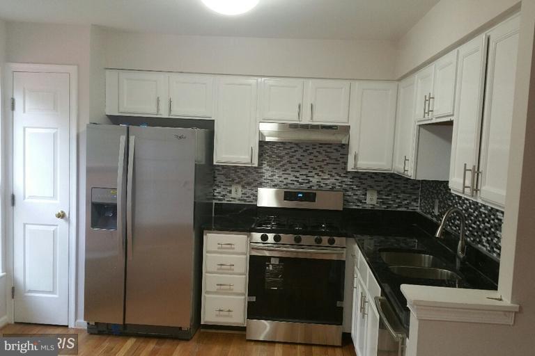 6367 Racetec Place Springfield, VA 22150 - Photo 2 of 25 a kitchen with stainless steel appliances wooden cabinets and a stove