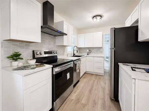 a kitchen with stainless steel appliances granite countertop a sink a stove a refrigerator and cabinets