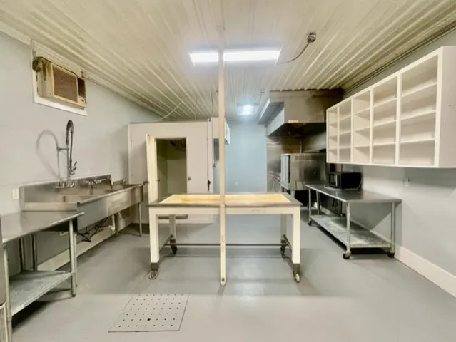 a kitchen with kitchen island granite countertop a stove top oven a sink a dining table and chairs