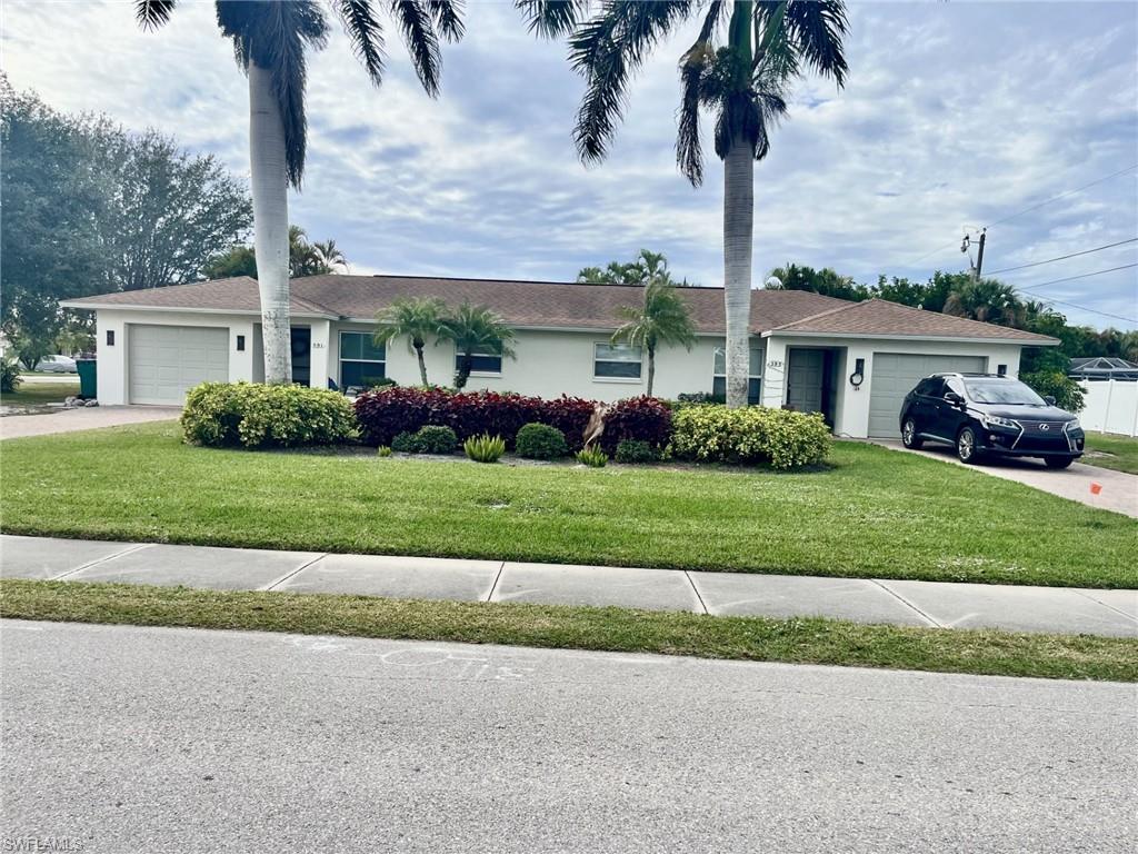 Single story home featuring an attached garage, a front yard, driveway, and stucco siding
