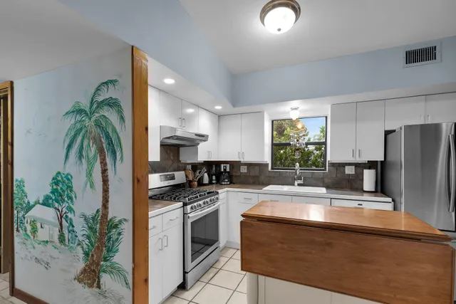 a kitchen with kitchen island a counter space a sink and stainless steel appliances