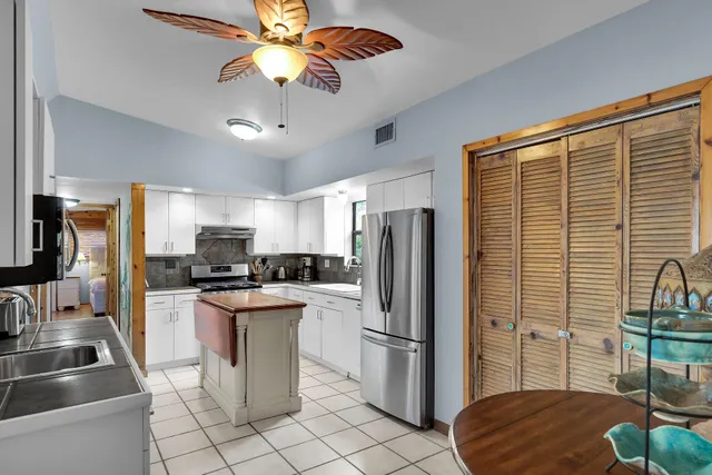 a kitchen with stainless steel appliances a refrigerator a sink a stove and white cabinets